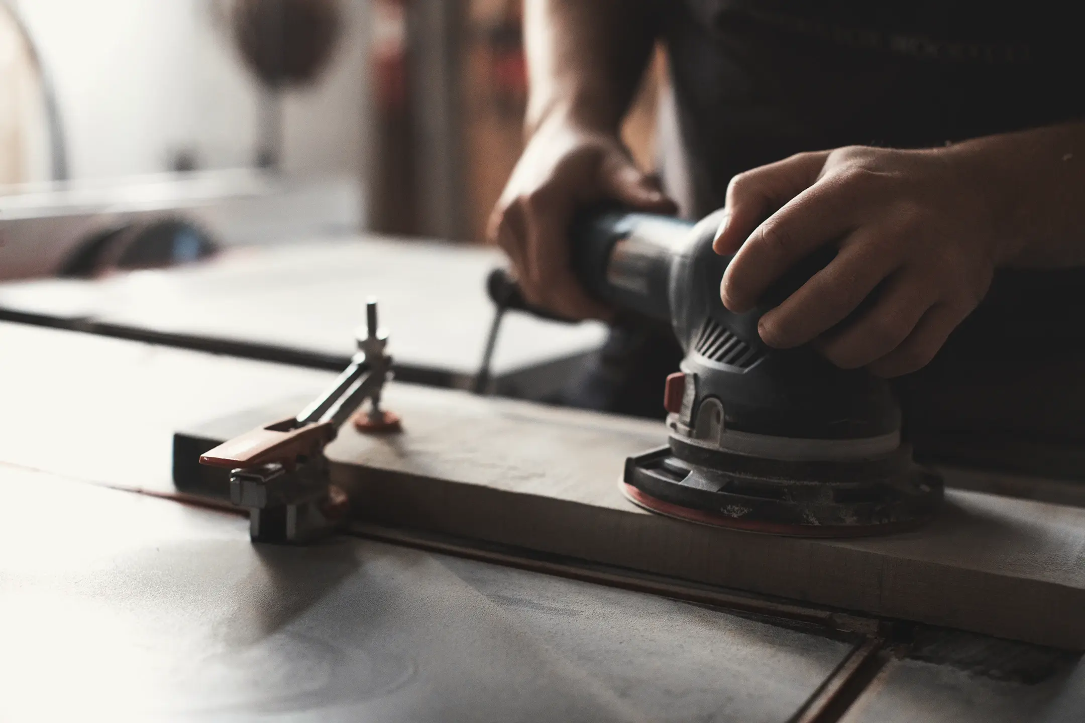 A craftsman shaping a solid ash tabletop by hand in a custom furniture workshop in Ontario, Canada.